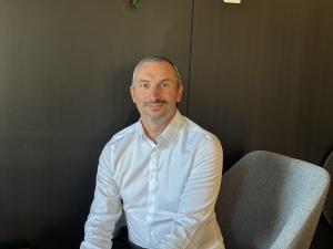 Un homme assis devant un fond noir.